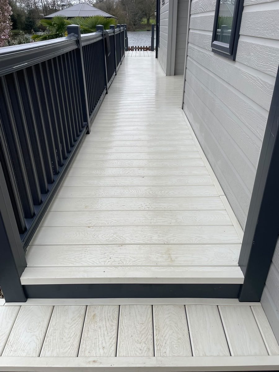 Pale composite decking after cleaning, with a dark glass balustrade