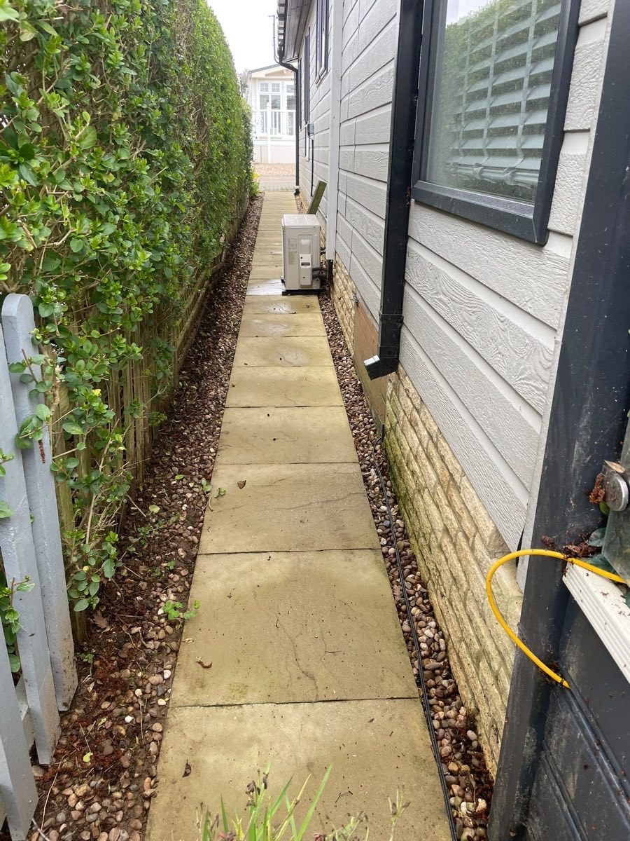 A narrow side path after cleaning, between a fence and a wall