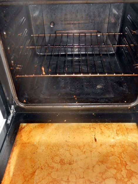 Inside a single electric oven before cleaning, burnt-on carbon across the base
