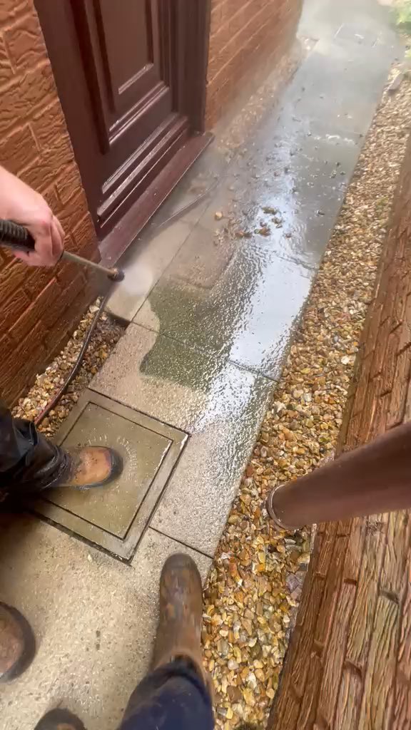 A path part-way through being jet washed, a clean stripe showing